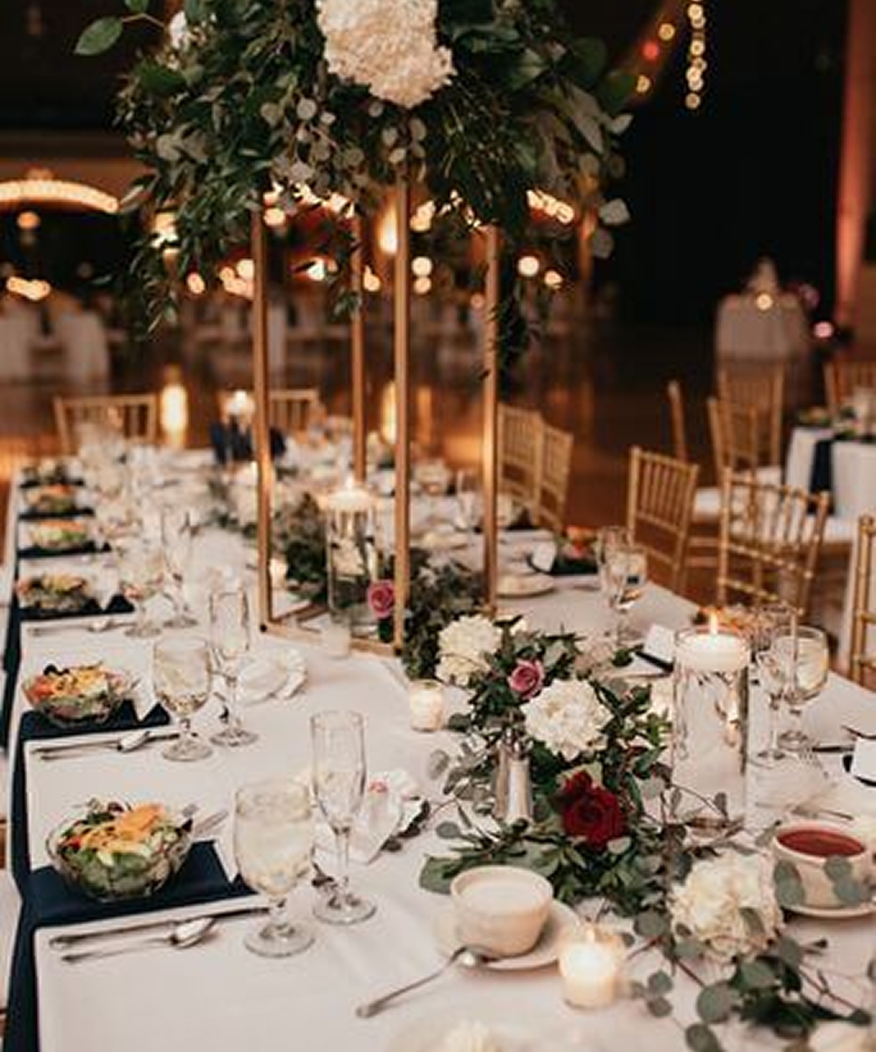 Elegant reception table with gold chairs, floral centerpieces, and candles at The Coliseum – St. Petersburg