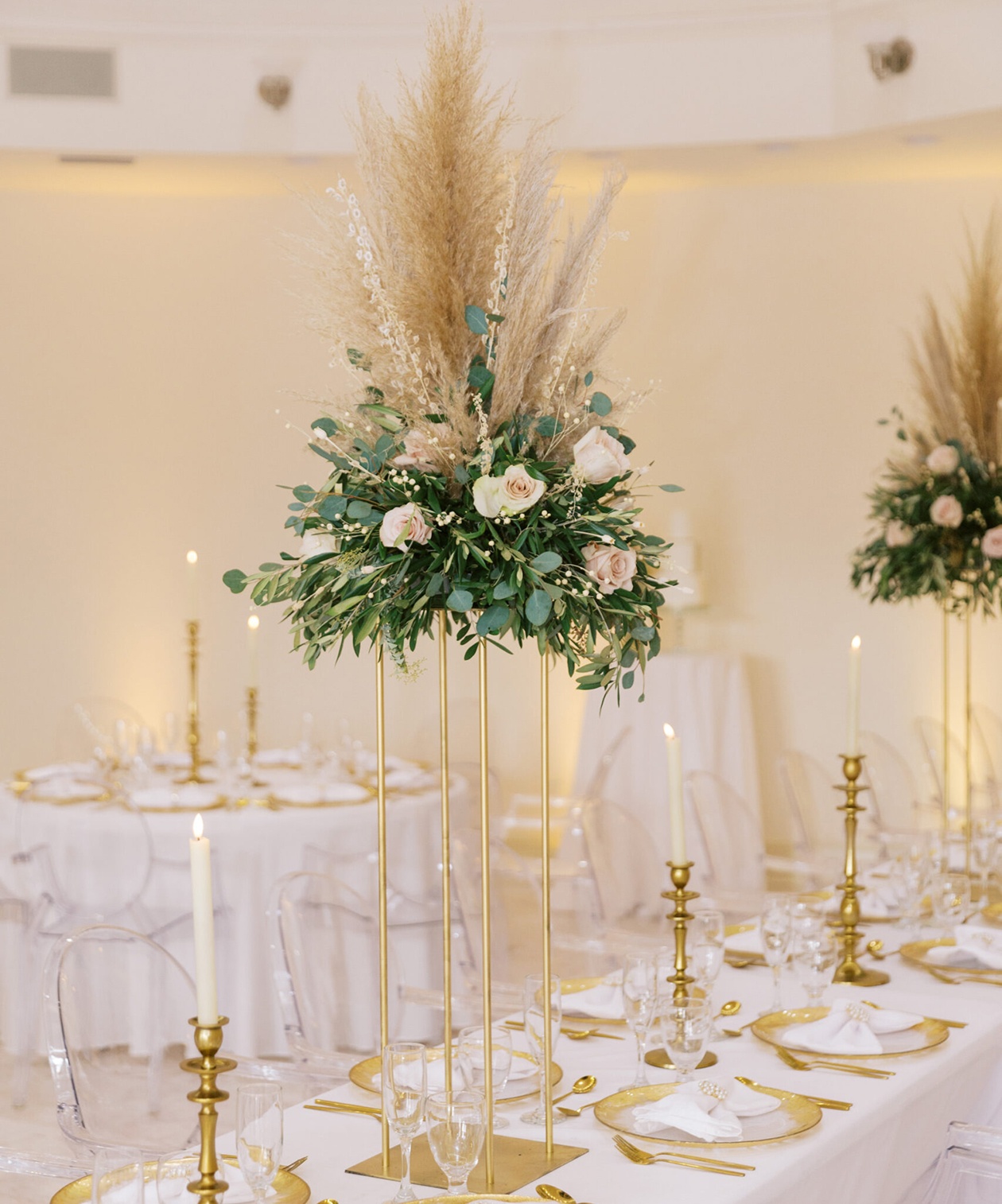 Elegant wedding table at Whitehurst Gallery with tall gold centerpiece of pampas grass, roses, and greenery