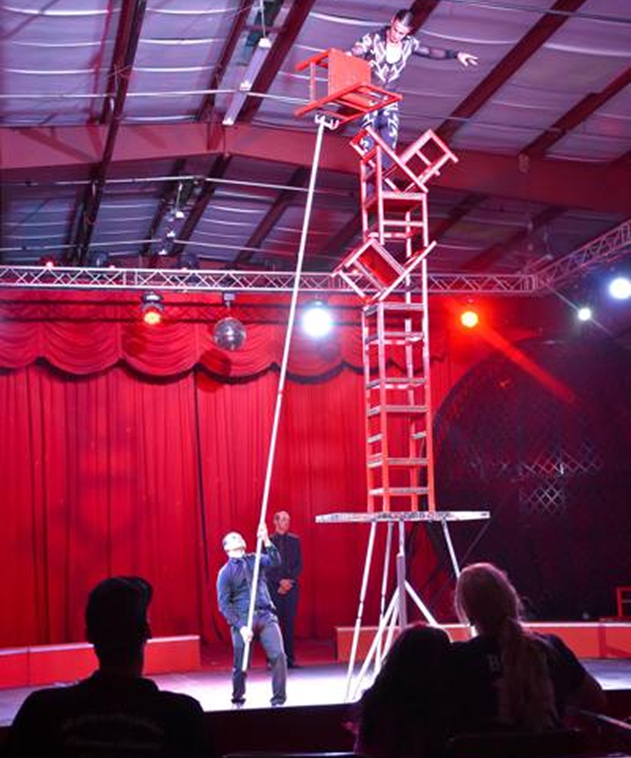 Circus-style performance at The Venue at Oldsmar Flea Market, with an acrobat balancing on chairs under stage lights