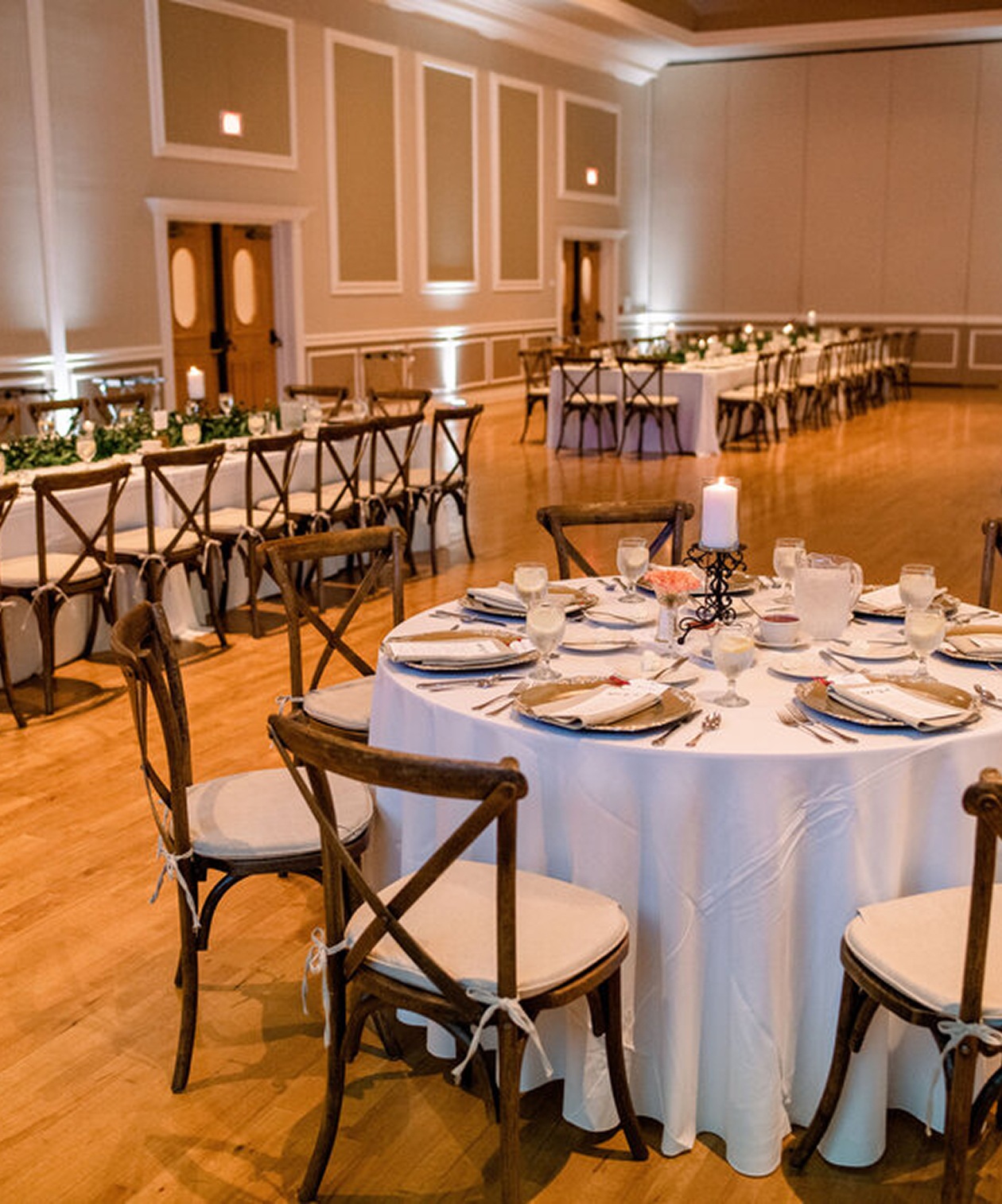 Wedding reception setup at The Ritz Ybor with round and long tables, wooden chairs, candles, and soft lighting