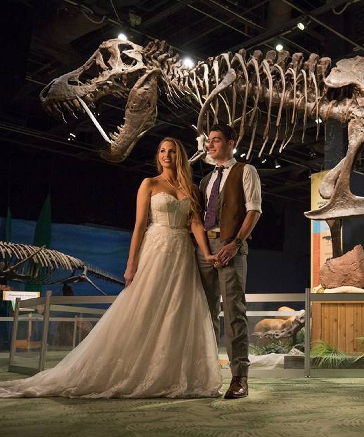 Bride and groom posing beneath a towering dinosaur skeleton display inside the Orlando Science Center wedding venue