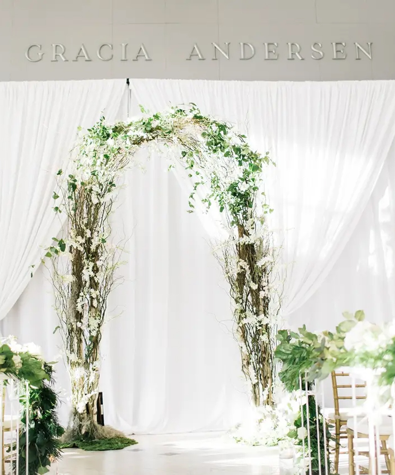 Elegant wedding ceremony arch of greenery and white florals at Orlando Museum of Art, set against soft white draping