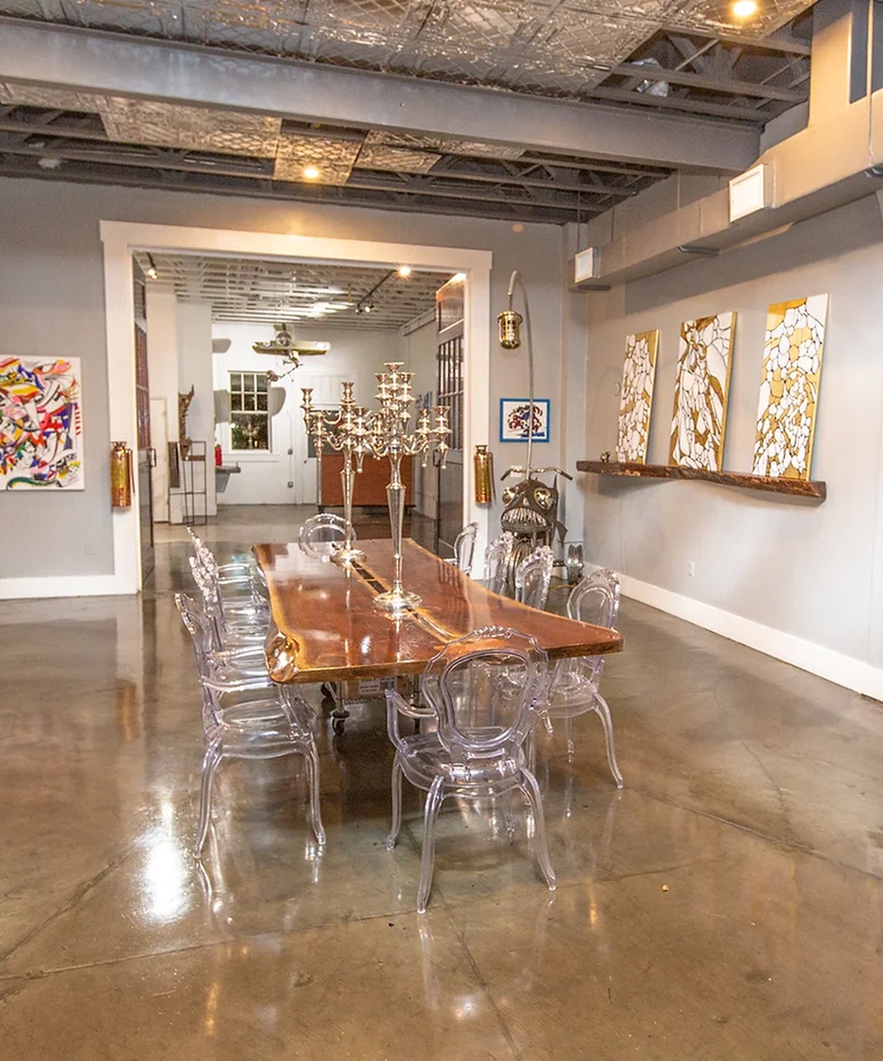 Artistic event space at Red Door No. 5 featuring polished floors, clear chairs, a wood table and gallery-style artwork