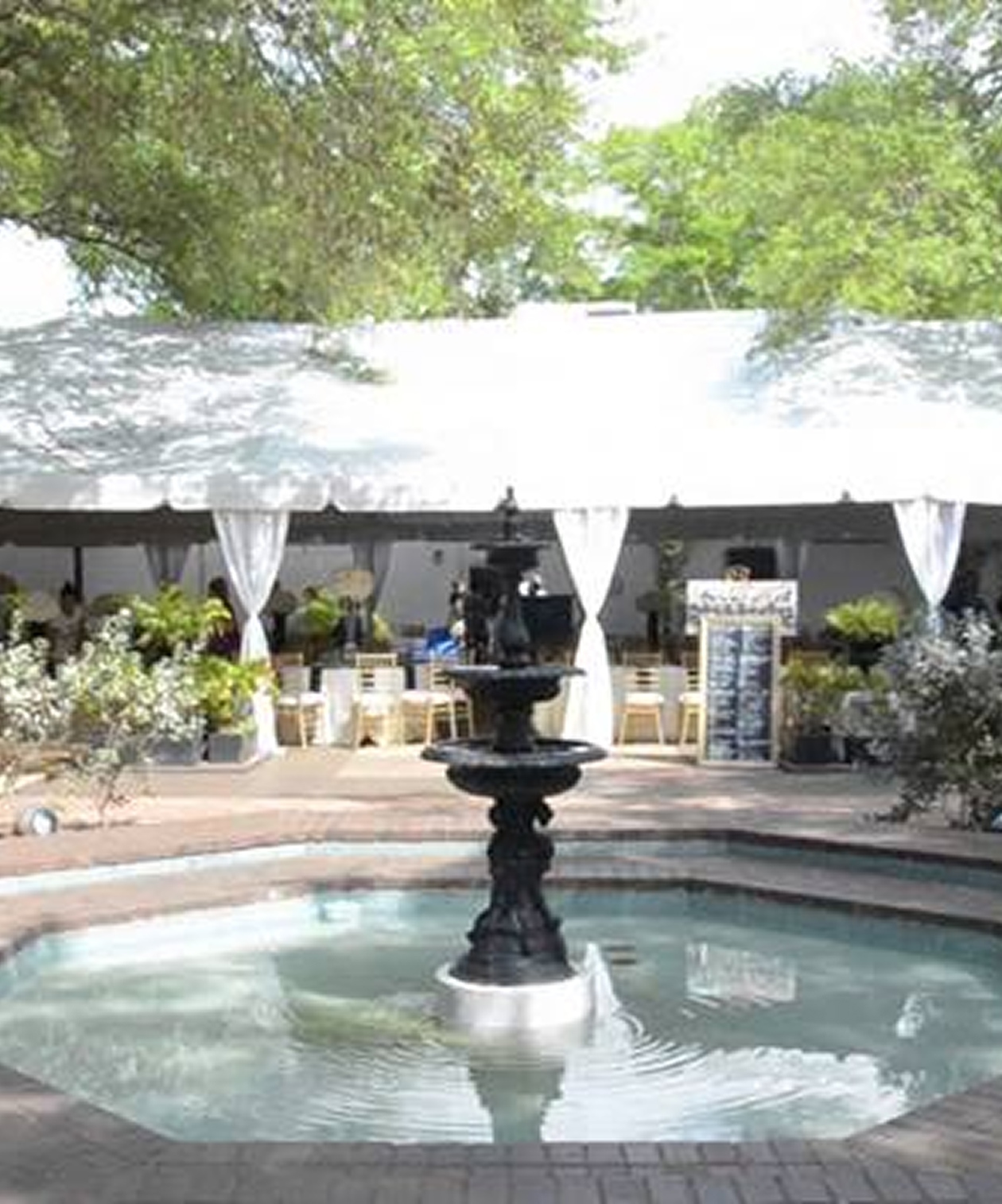 Outdoor wedding setup at Ybor City Museum State Park with a central fountain, draped tent, and garden greenery