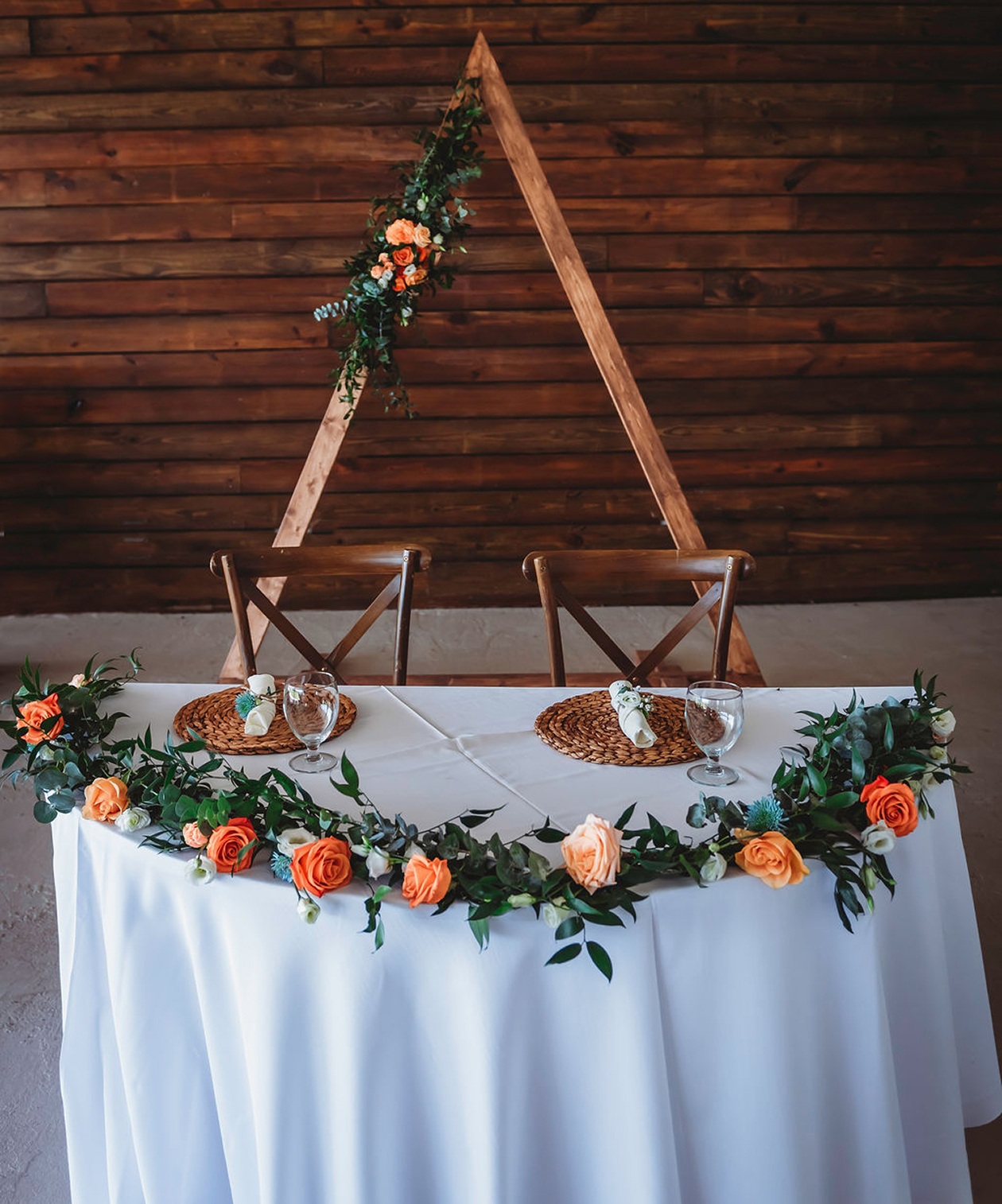 Sweetheart table with peach and cream florals against rustic wooden backdrop at Happy Hearts Barn