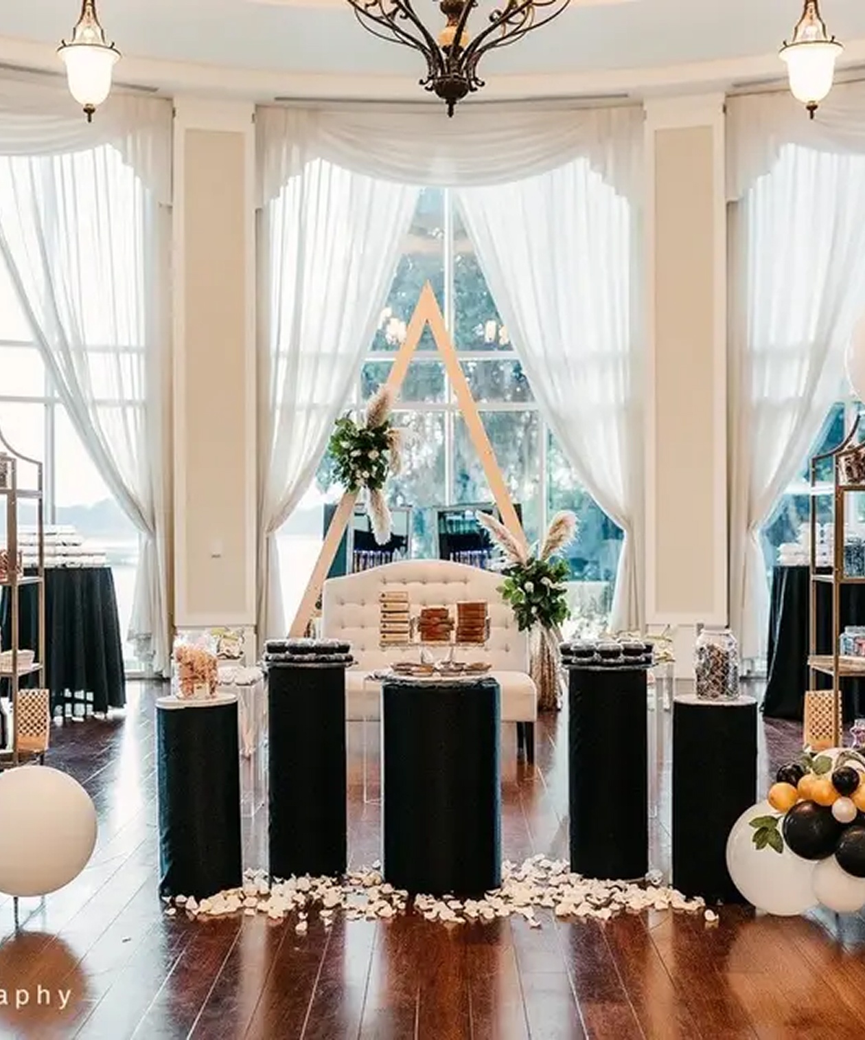 Elegant event setup at Lake Mary Events Center with tall draped windows, floral decor, and modern dessert displays