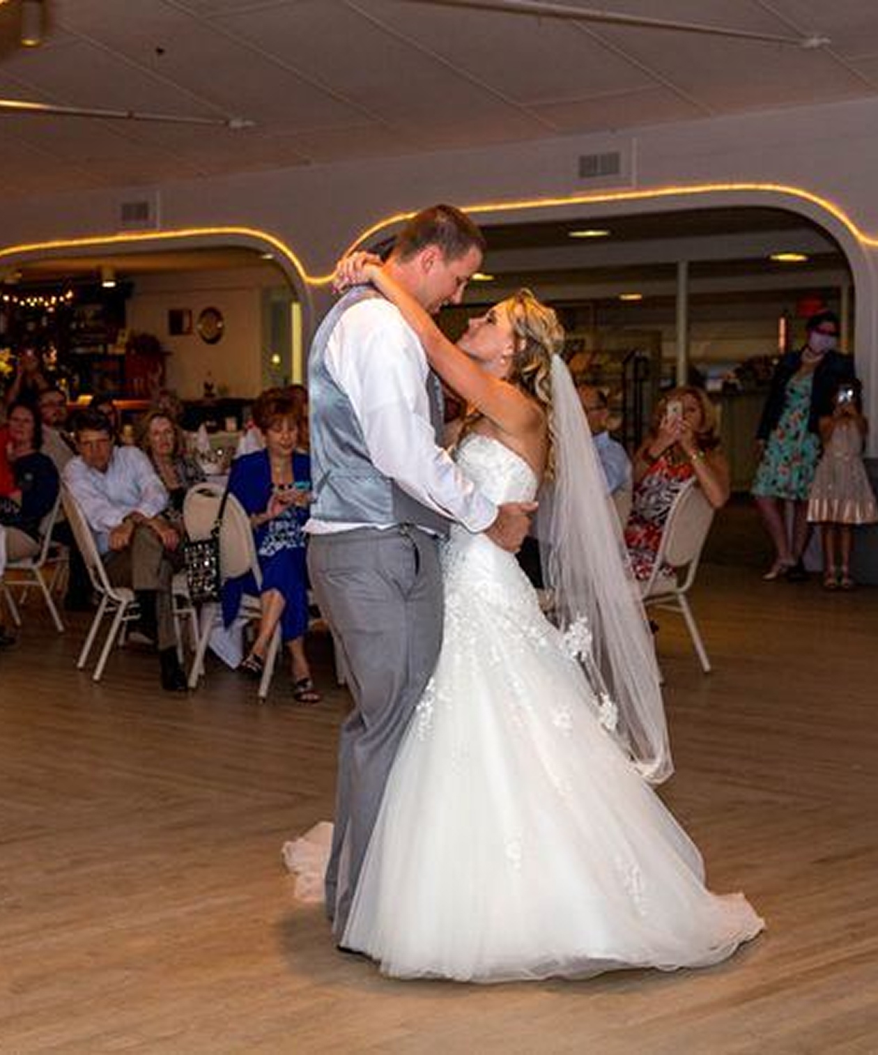 Bride and groom sharing their first dance at Gulfport Casino Ballroom, surrounded by guests and warm ambient lighting