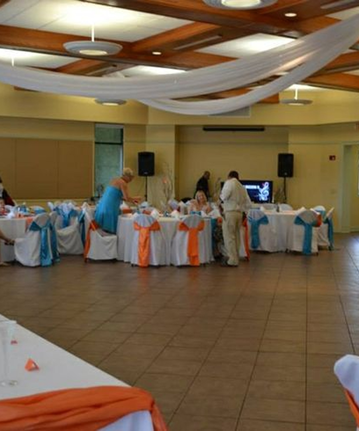 Wedding reception setup at The Peggy Brown Building with draped ceilings and chairs tied in blue and orange sashes