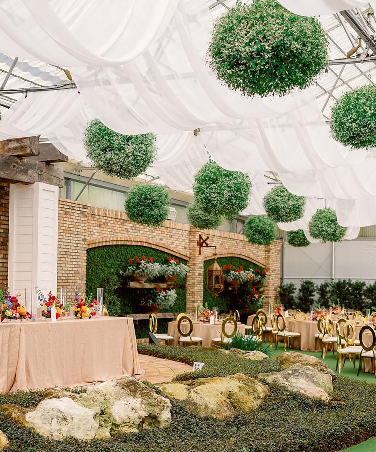 Hardeman’s Secret Garden indoor venue with draped white fabric, hanging green spheres, floral decor and banquet tables