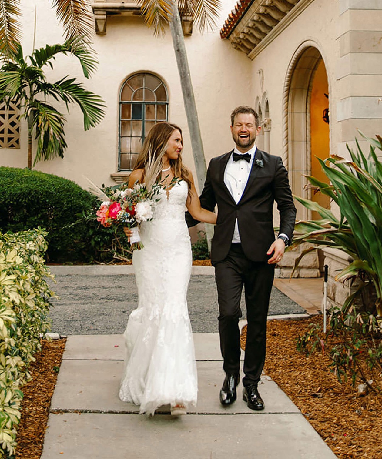 Bride and groom walking outside the Powel Crosley Estate, surrounded by greenery and Mediterranean-style architecture
