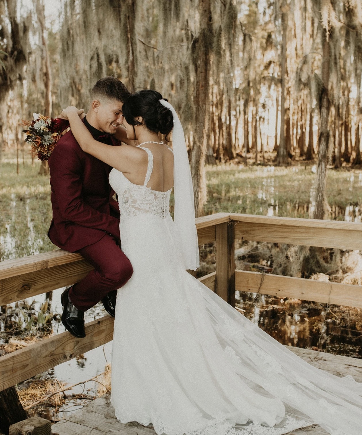 Bride and groom embracing on a wooden walkway at Lovelock Ranch, surrounded by moss-draped trees and peaceful nature