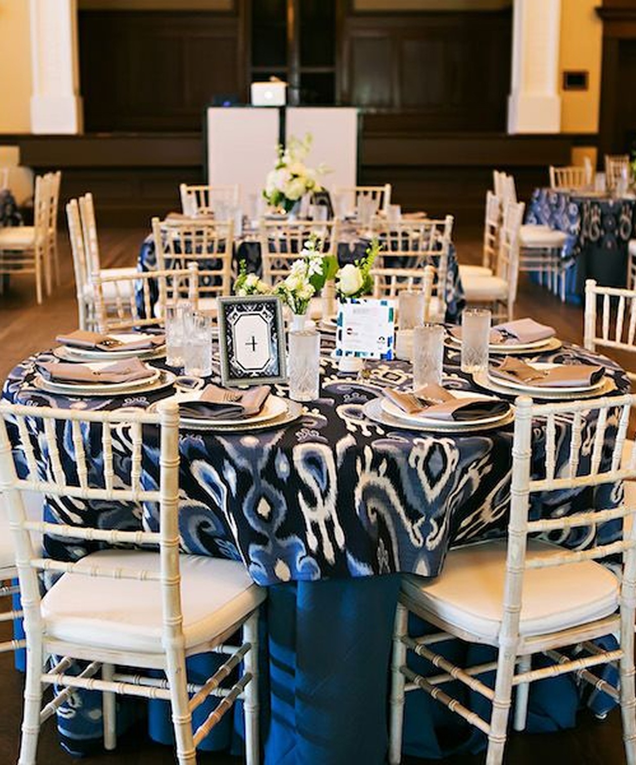 Reception setup at Junior League Sorosis Building with patterned navy linens, white chairs, and floral centerpieces