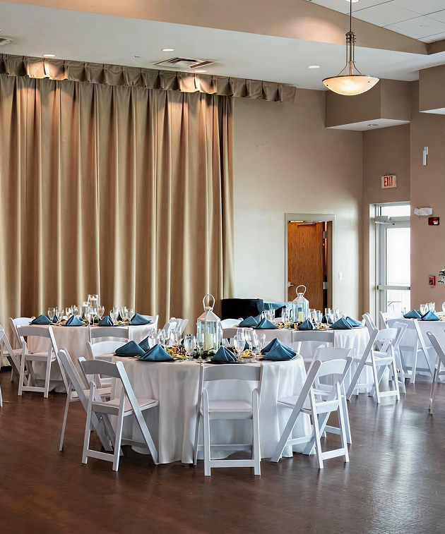 Elegant reception setup at St. Pete Beach Community Center with round tables, white chairs, and navy napkins