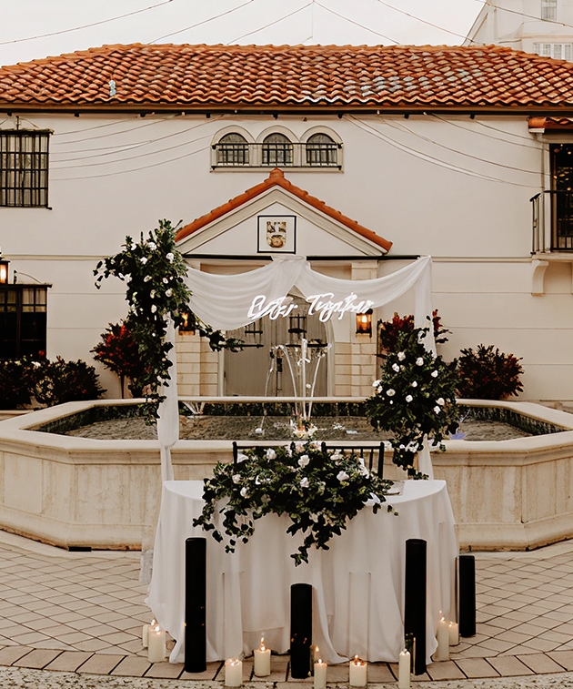 Outdoor wedding setup at The Bishop Museum of Science and Nature featuring a fountain, candles, and floral decor