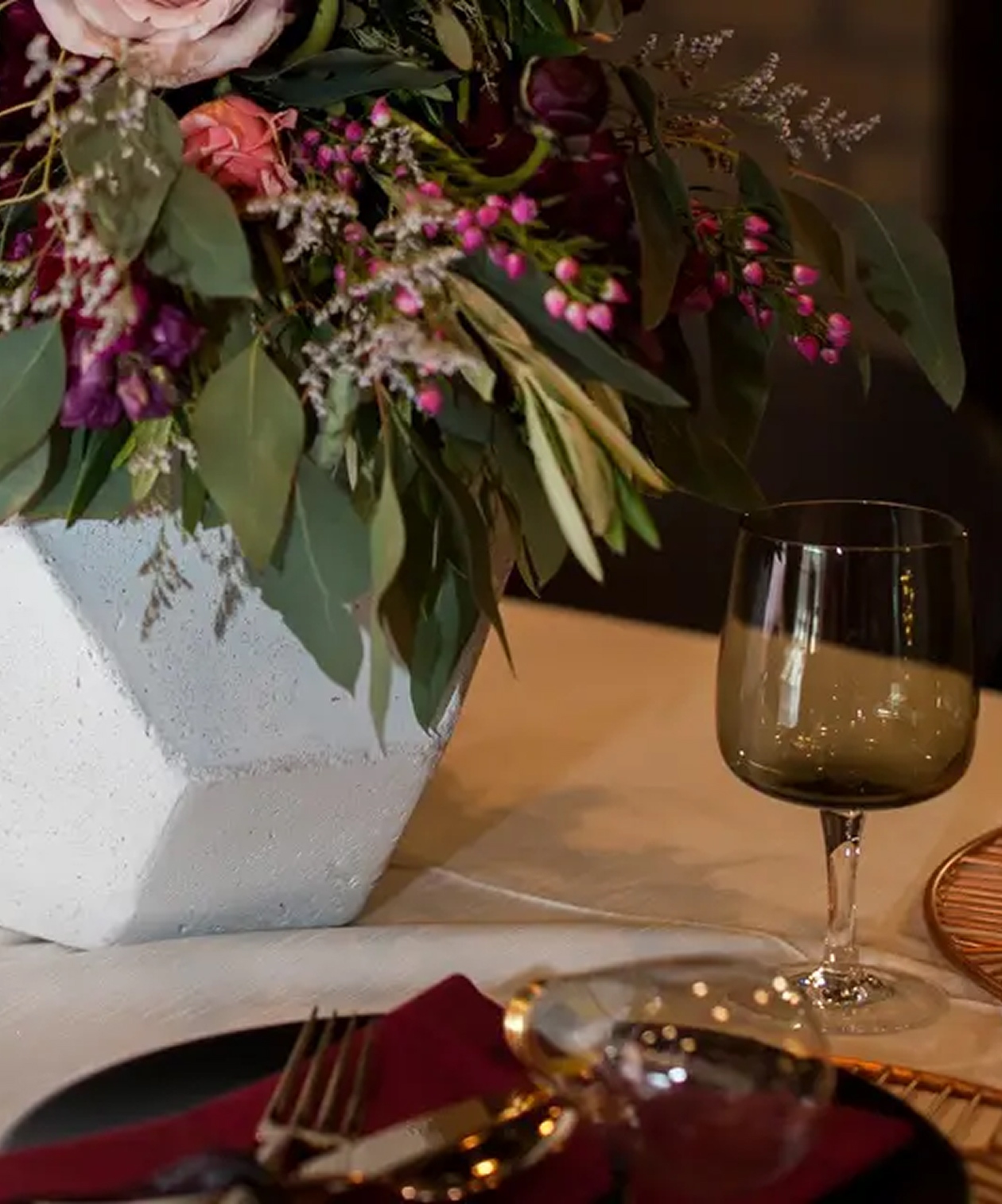 Elegant table at Kozuba & Sons Distillery featuring a floral centerpiece, dark glassware, and warm romantic tones