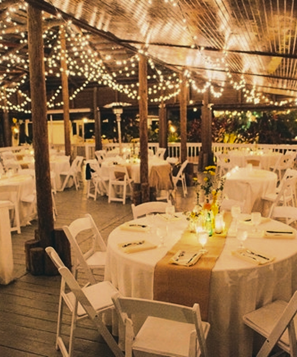 Paradise Cove Orlando outdoor reception with round tables, white chairs, warm string lights, and tropical surroundings