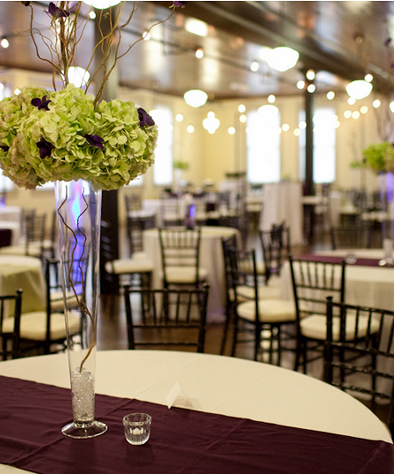 Tampa Firefighters Museum reception setup with round tables, tall floral centerpieces, and warm ambient lighting