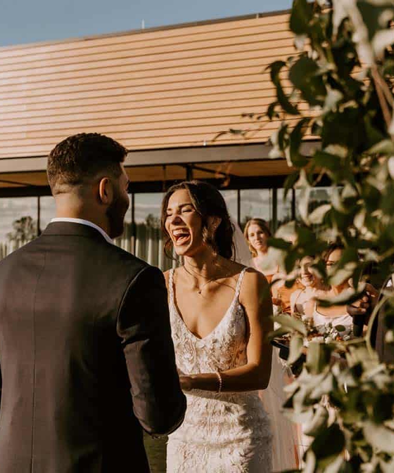 Bride laughing joyfully during the ceremony at Bonnet Springs Park, standing beside the groom
