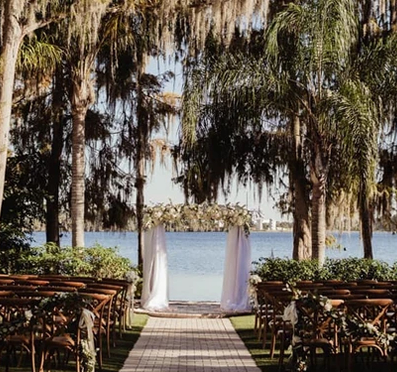 Outdoor tiki-style setup at Paradise Cove Orlando with cocktail tables, palm trees, and glowing string lights