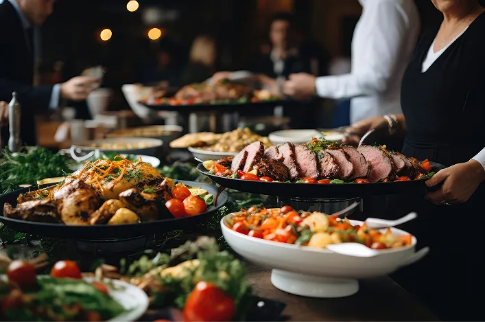 Buffet table with sliced roast, roasted meat, and vibrant salads, served by staff during an elegant catered event