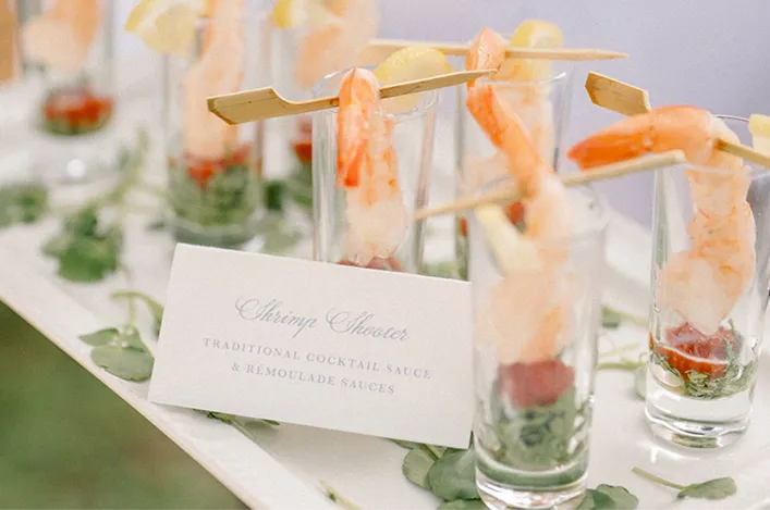 Shrimp shooters served in tall glasses with cocktail sauce and lemon garnish, displayed as elegant appetizers