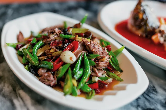 Stir-fried beef with peppers, garlic, and green onions served on a white platter