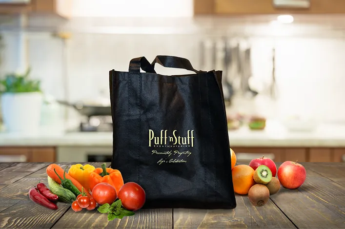 Puff 'n Stuff tote bag on a wooden table surrounded by fresh fruits and vegetables, with a softly blurred kitchen backdrop