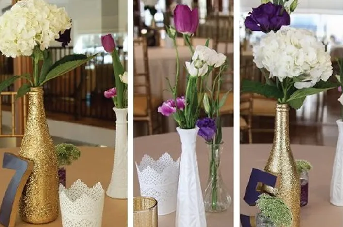 Gold and white vases filled with hydrangeas and colorful flowers decorate wedding tables with table numbers and candles
