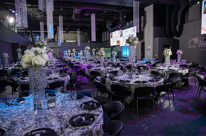 Elegant banquet hall with round tables, crystal centerpieces, and dramatic purple lighting set for a formal evening event